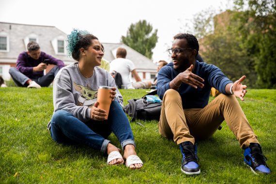 Foto with two people sitting on lawn appearing to be in conversation with each other